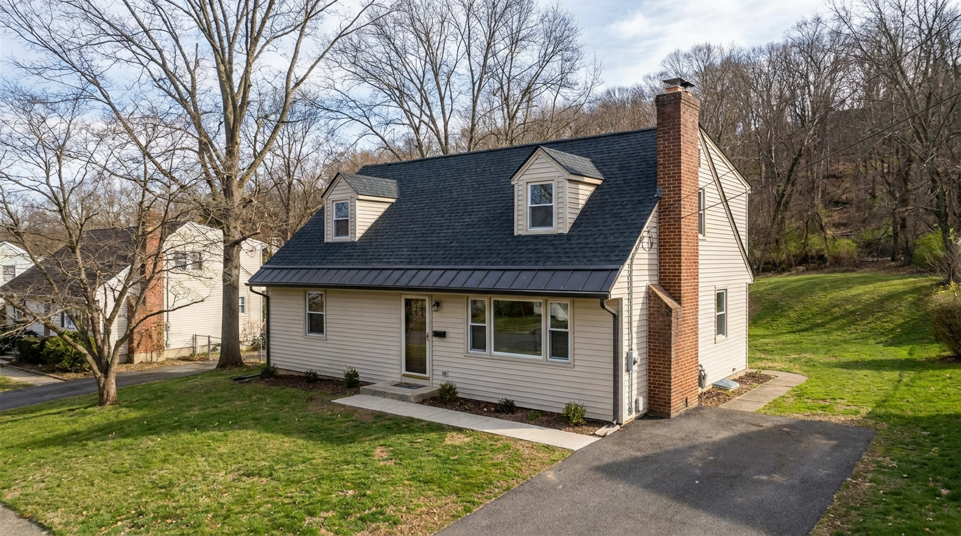 Cape Cod-style home on a gently sloping Woodland Park-style residential lot with a new dark architectural shingle roof and mature trees.